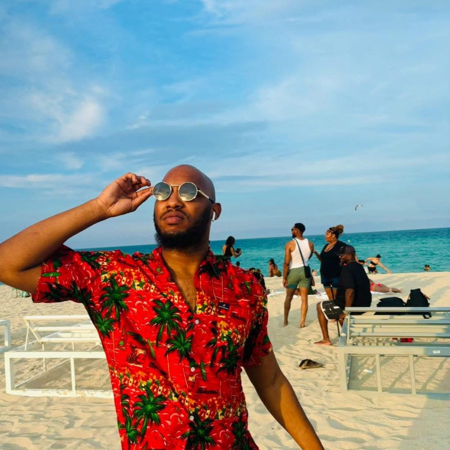 EJ Fields at the beach in a red palm tree shirt and round sunglasses